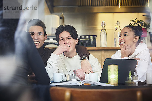 Lächelnde männliche und weibliche Teenager-Freunde sitzen am Tisch im Restaurant