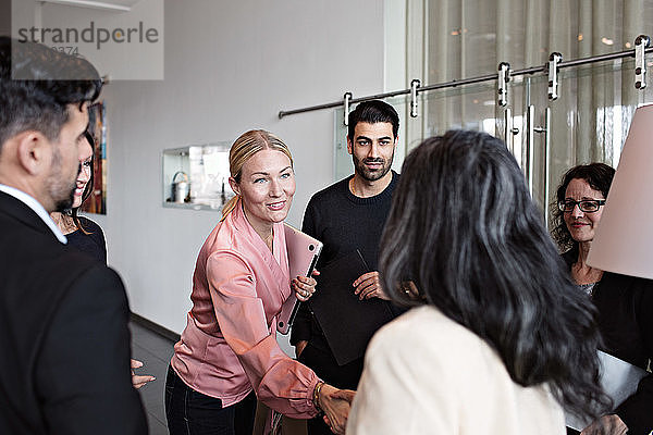 Begrüßung von Geschäftsfrauen im Stehen mit Kollegen in der Lobby im Büro