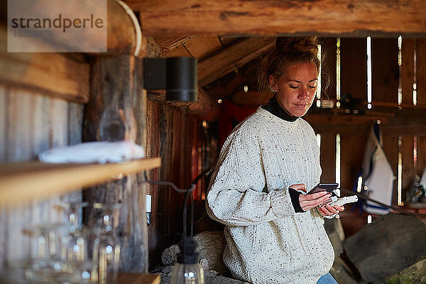 Mittlere erwachsene Frau  die ein Smartphone benutzt  während sie in einer Hütte steht