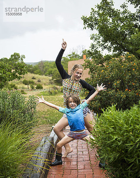 5 Jahre alter Junge und seine 13 Jahre alte Schwester tanzen im Regen.