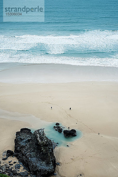 Hochwinkelaufnahme von Meereswellen und Felsen an einem Sandstrand.