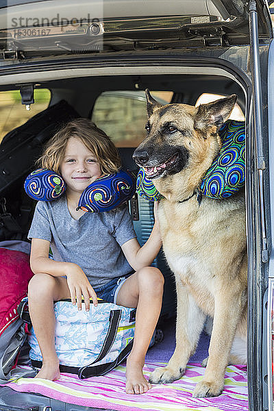 5 Jahre alter Junge mit seinem Deutschen Schäferhund  auf dem Rücksitz eines SUV