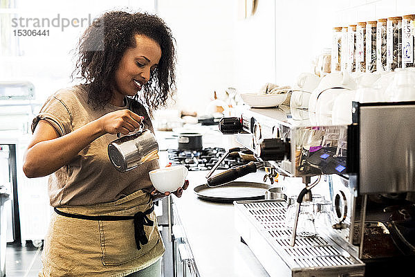 Barista-Frau  die in einem Café eine Tasse Kaffee zubereitet.