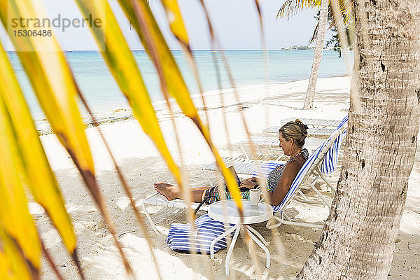 erwachsene weibliche Führungskraft mit Laptop am Strand