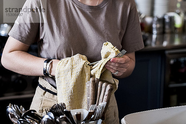 Ein Mitarbeiter trocknet Besteck in einem Cafe.