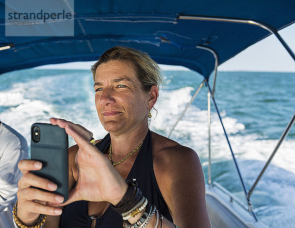 Erwachsene Frau beim Fotografieren mit Smartphone  auf Boot