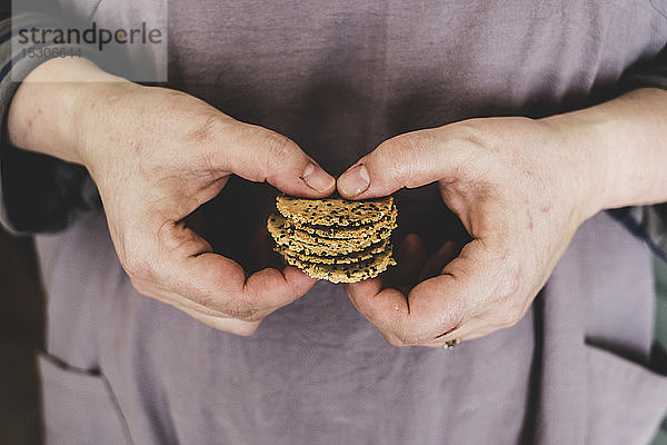 Nahaufnahme einer Person  die einen kleinen Stapel frisch gebackener  entkernter Cracker hält.