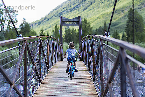 Rückansicht eines 5 Jahre alten Jungen auf einer schmalen Brücke über einen Berg