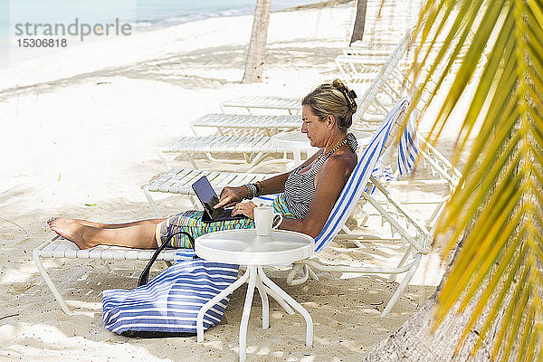 erwachsene weibliche Führungskraft mit Laptop am Strand