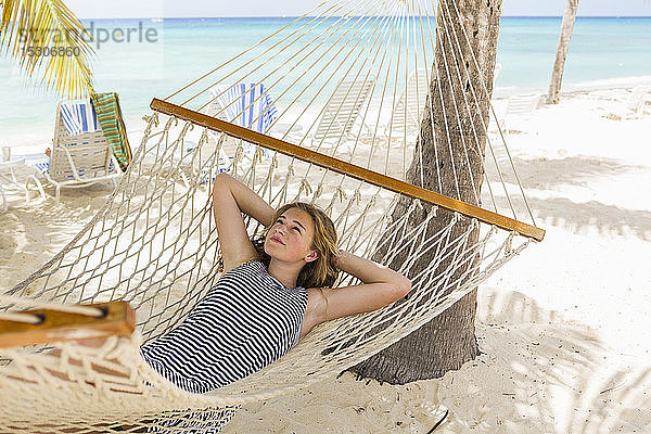 Ein jugendliches Mädchen entspannt sich in einer Hängematte am Strand