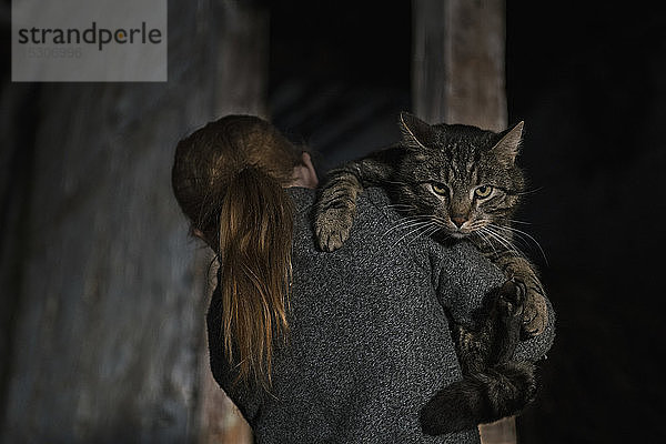 Mädchen hält Katze über der Schulter