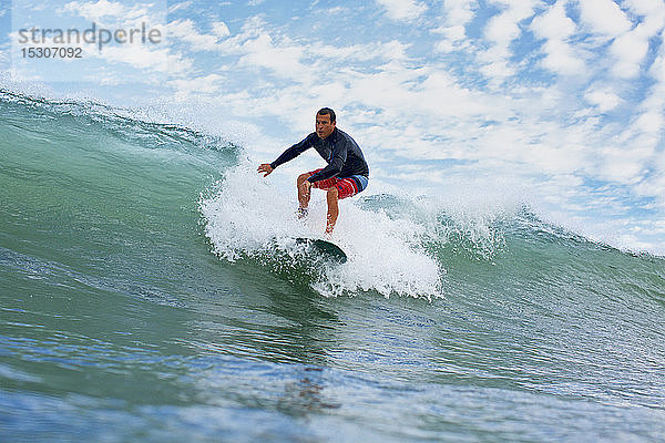 Männlicher Surfer reitet auf einer Meereswelle