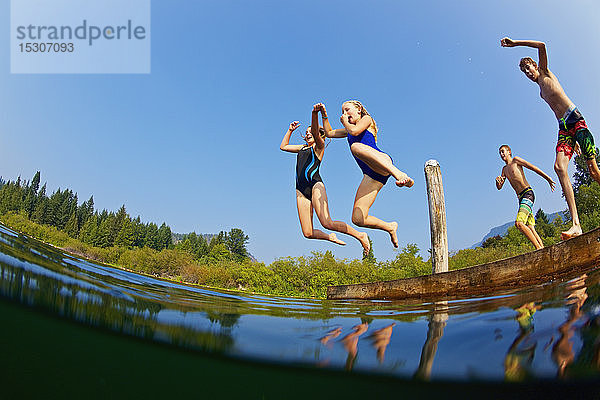 Kinder springen in den sonnigen Sommersee