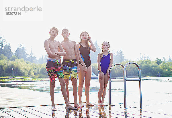 Portrait tween Freunde in Badeanzügen stehen auf sonnigen See-Dock