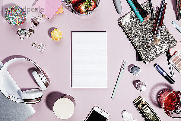 Ansicht Formular über leeren Notizblock umgeben von persönlichen Gegenständen auf rosa Hintergrund