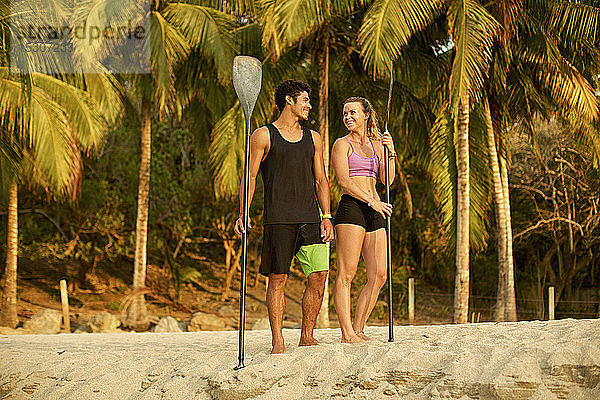 Junges Paar mit Rudern am sonnigen  tropischen Strand