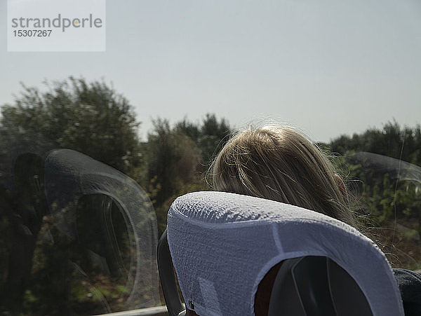 Frau im Zug  die sich entspannt und aus dem sonnigen Fenster schaut