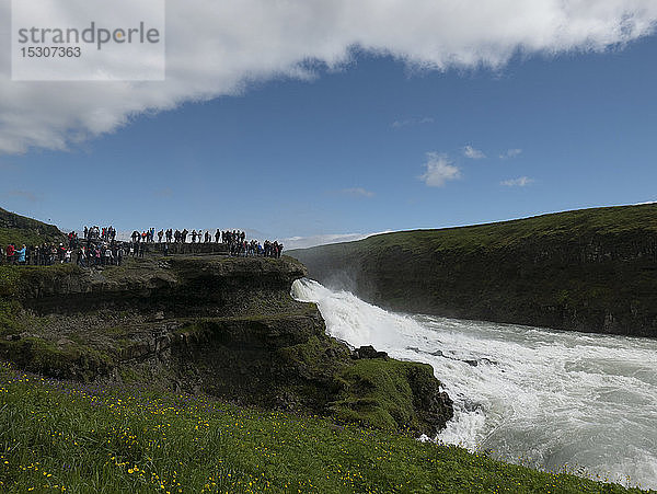 Touristen mit Blick auf einen sonnigen  malerischen Wasserfall  Gullfoss  Island