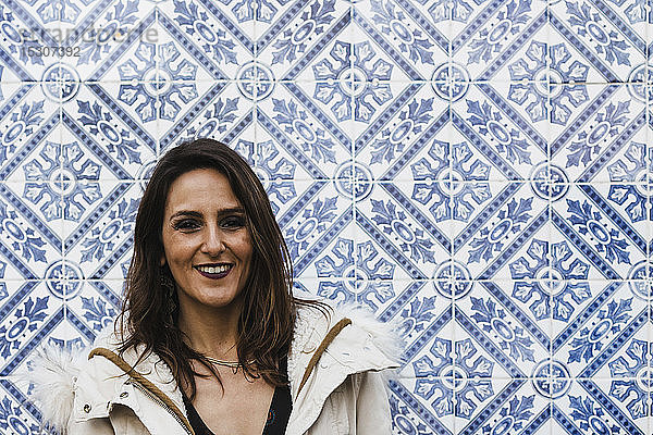 Porträt glückliche Frau stehend gegen blaue und weiße Mosaikwand