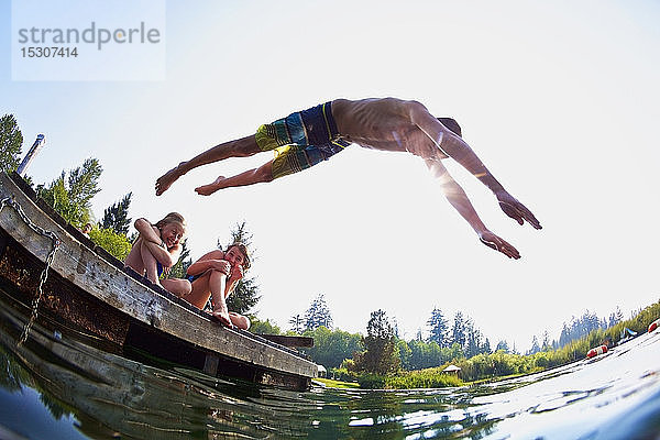 Junge springt vom Steg in den sonnigen Sommersee