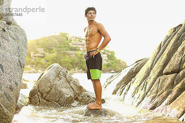 Junger  fitter Mann steht auf einem Felsen im Meer  Sayulita  Nayarit  Mexiko