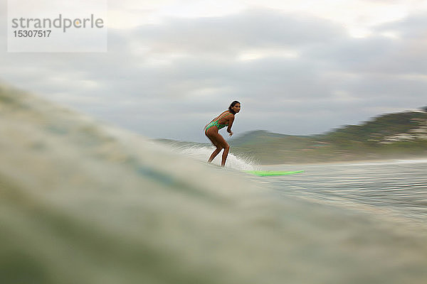 Weibliche Surferin reitet auf einer Meereswelle