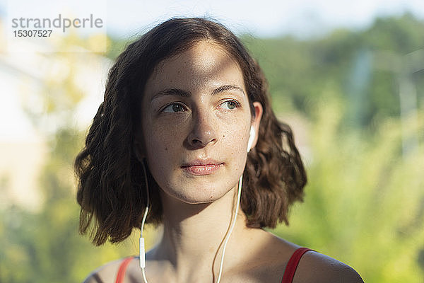 Nachdenkliche Frau  die mit Kopfhörern Musik hört