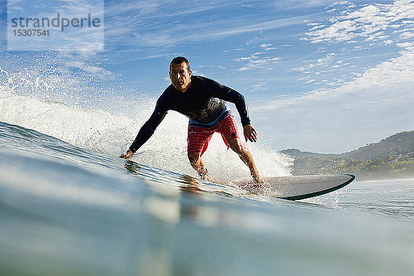 Männlicher Surfer reitet auf einer Meereswelle