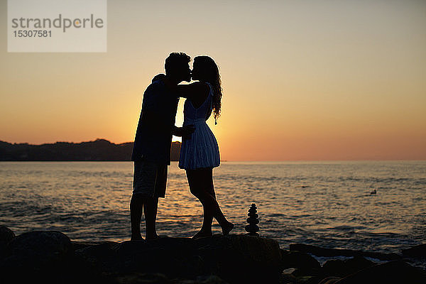 Silhouette junges  romantisches Paar  das sich am idyllischen Strand bei Sonnenuntergang küsst  Sayulita  Nayarit  Mexiko