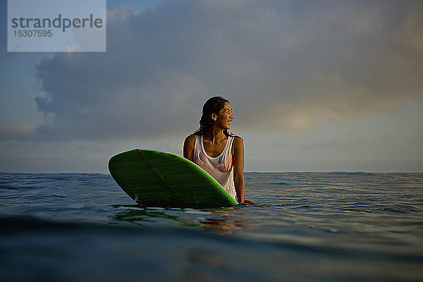 Weibliche Surferin wartet auf dem Surfbrett im Meer
