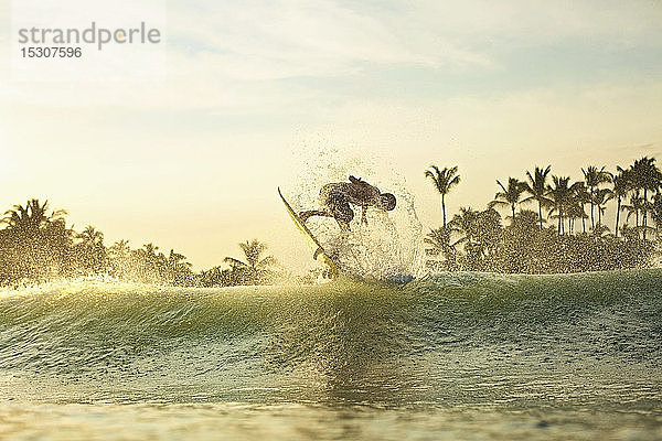 Männlicher Surfer  der bei Sonnenaufgang hinter einer Welle Luft holt  Sayulita  Nayarit  Mexiko