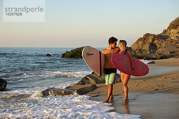 Junges  zärtliches Paar mit Surfbrettern am sonnigen Strand  Sayulita  Nayarit  Mexiko
