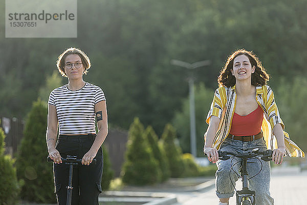 Porträt Frauen Freunde fahren Fahrrad und schieben Roller