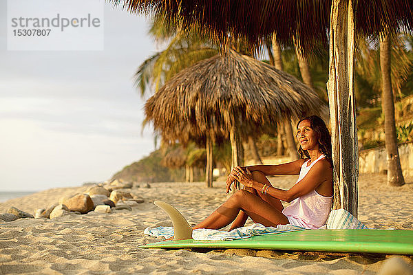 Weibliche Surferin mit Surfbrett entspannt am sonnigen Strand  Sayulita  Nayarit  Mexiko