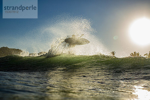 Surfer  der bei Sonnenaufgang hinter einer Welle Luft schnappt  Sayulita  Nayarit  Mexiko