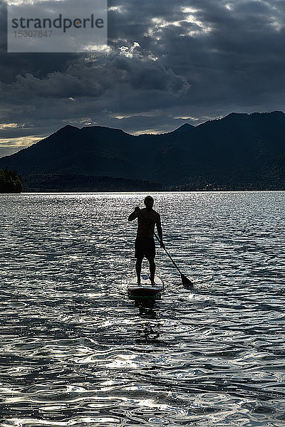Silhouette Mann beim Paddeln auf einem sonnigen  idyllischen See  Walchensee  Bayern  Deutschland