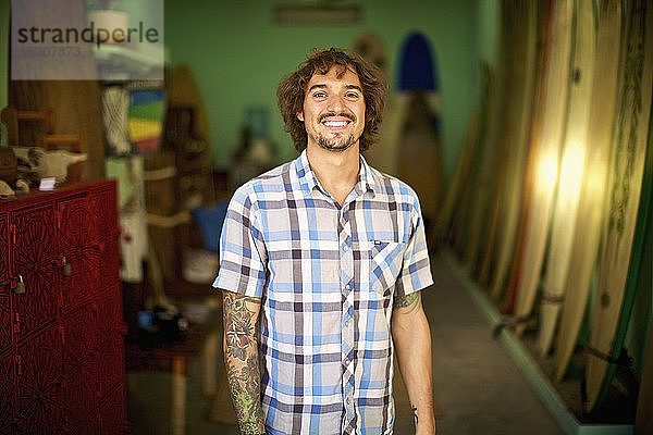 Porträt selbstbewusster  glücklicher männlicher Surfshop-Besitzer