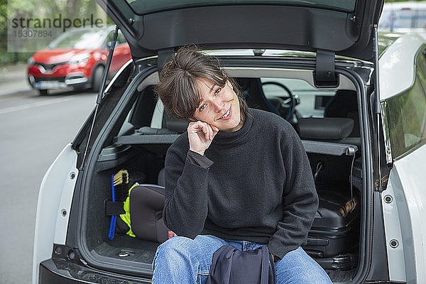 Porträt einer lächelnden jungen Frau auf der Rückbank eines Autos