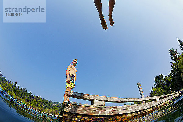 Jungen springen vom Steg in den sonnigen Sommersee