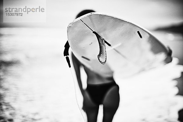 Weibliche Surferin mit Surfbrett am Meeresstrand