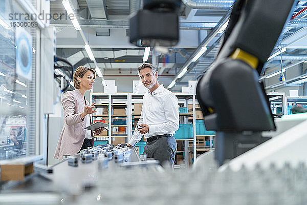 Geschäftsmann und Geschäftsfrau im Gespräch in einer modernen Fabrikhalle