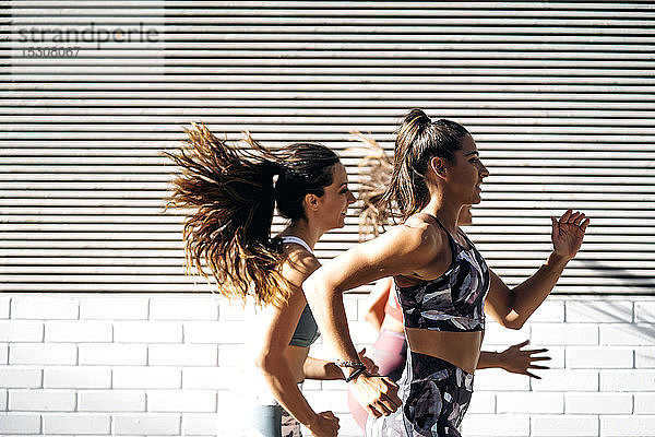 Drei sportliche junge Frauen laufen in der Stadt