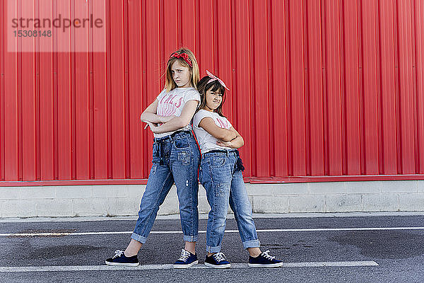 Zwei Schwestern stehen vor einer roten Wand