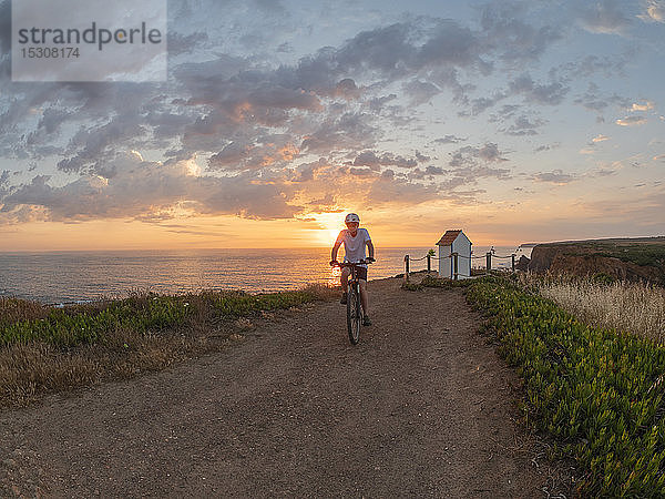 Portugal  Alentejo  älterer Mann auf E-Bike bei Sonnenuntergang
