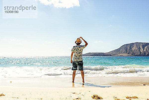 Rückansicht eines Mannes mit Hut an der Playa de las Conchas  Lanzarote  Kanarische Inseln  Spanien