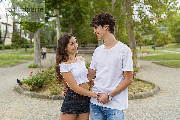 Junges Paar hält Händchen in einem Park