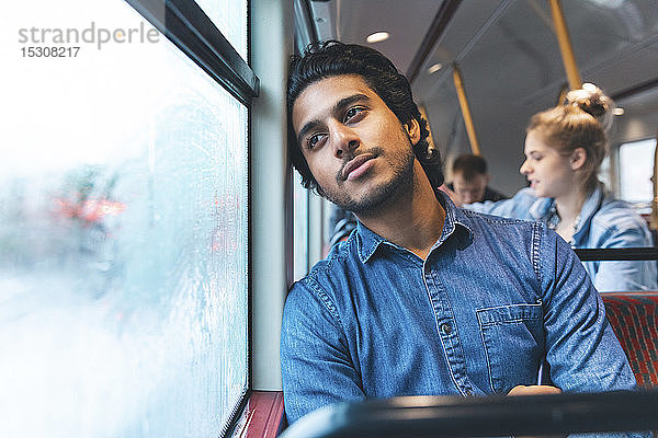 Porträt eines tagträumenden jungen Mannes  der mit dem Bus reist  London  UK