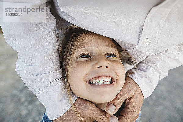 Porträt eines glücklichen Mädchens  das von seinem Vater umarmt wird