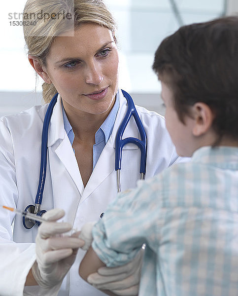 Ärztin gibt einem kleinen Jungen in der Klinik eine Impfung