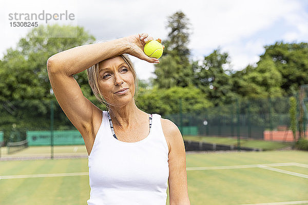 Müde Tennisspielerin macht eine Pause auf dem Rasenplatz des Tennisclubs